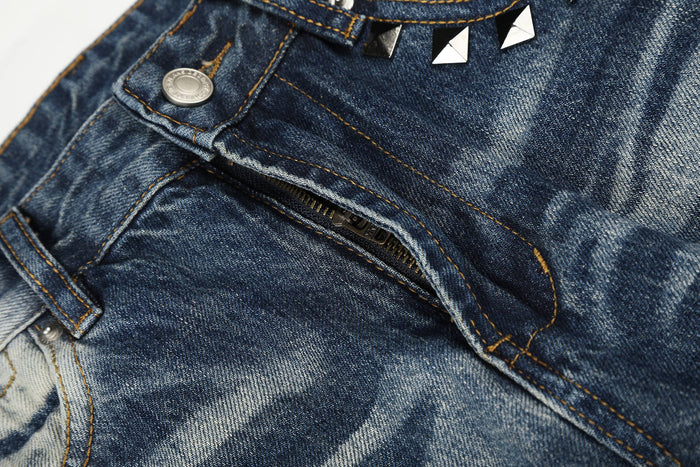 Close-up of front fly on vintage wash jeans showing zipper and studded pocket edge