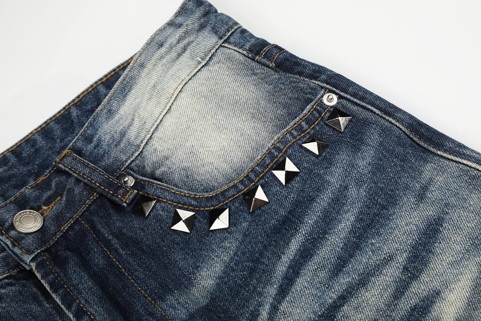 Close-up of front pocket and studded trim on blue faded denim jeans