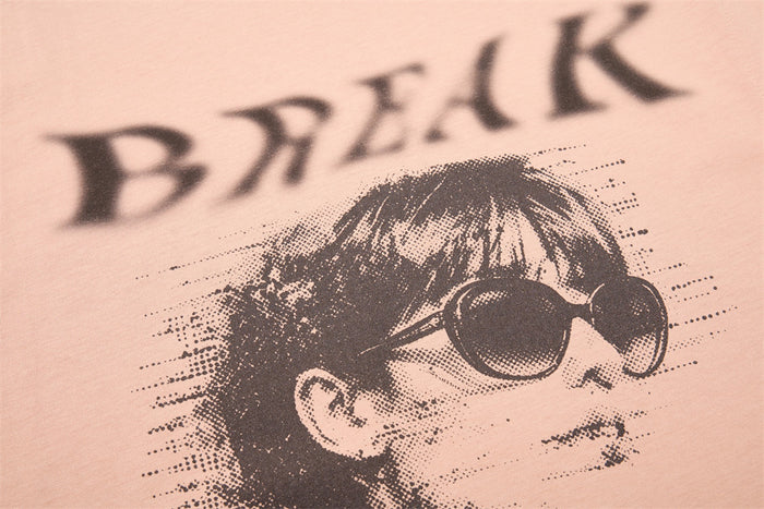 Close-up of BREAK text above portrait graphic on beige tank top