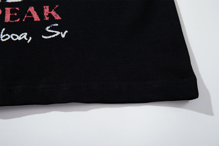 Close-up of the black T-shirt bottom hem showing stitched edging and partial graphic lettering