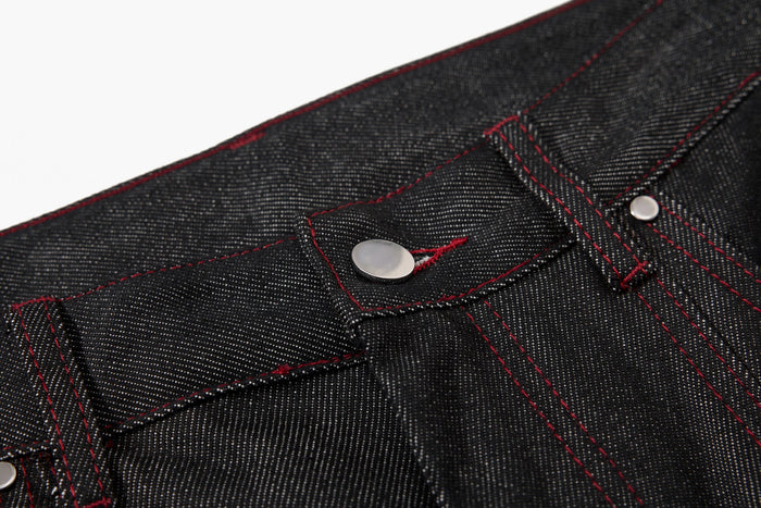 Close-up of black denim waistband button and stitching detail