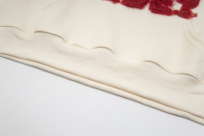 Cream hoodie hem close-up showing ribbed cuff and smooth fabric seam
