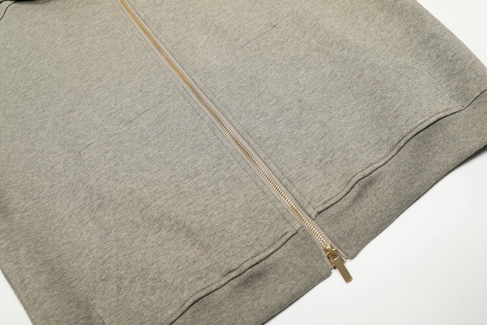 Close-up of beige zip-up hoodie front with gold zipper and kangaroo pocket edge
