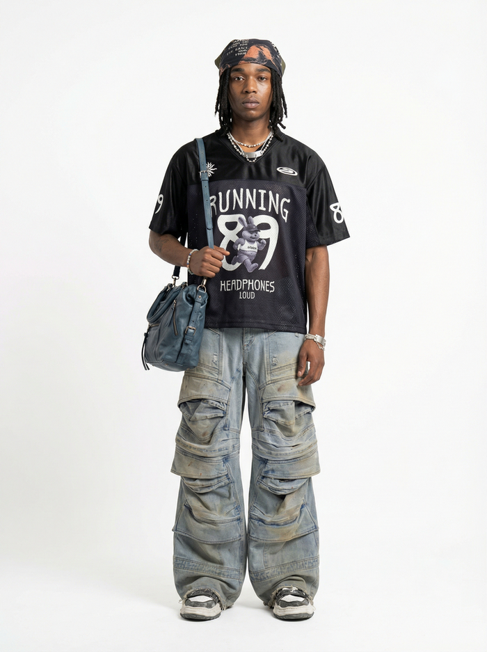 Model wearing a black mesh jersey with Running 89 graphic, styled with baggy cargo jeans and a blue shoulder bag