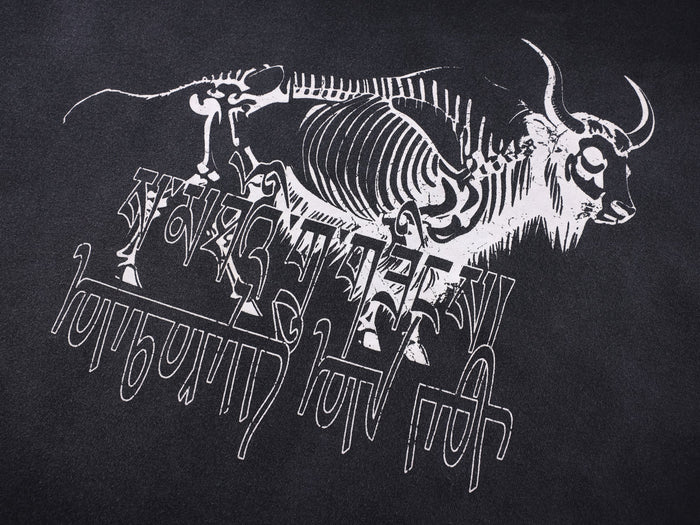 Close-up of white skeleton bull graphic and layered text print on black fabric