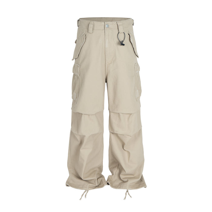 Beige wide-leg cargo pants with multi-pocket design, drawstring hems, and metal ring hardware, front view