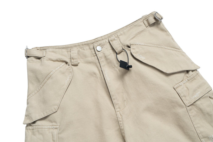 Beige cargo pants waistband with buckle strap, snap button and zipper detail