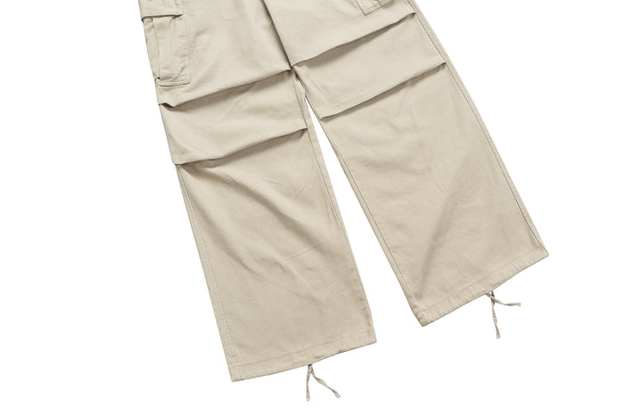 Beige wide-leg cargo pant legs with oversized pocket flaps and drawstring hems