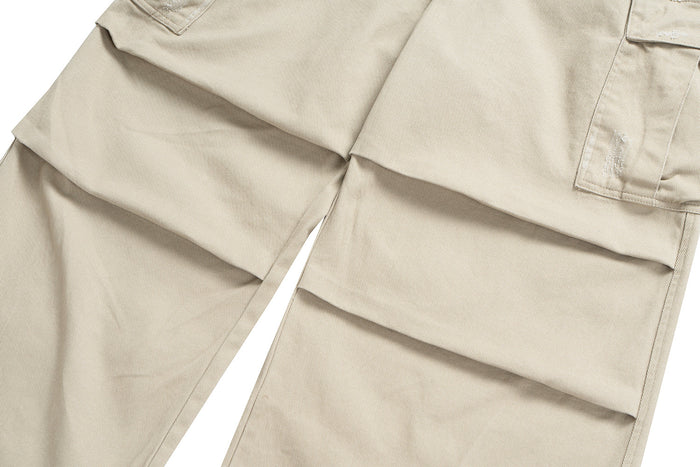 Beige cargo pants close-up showing layered pocket flaps and seams