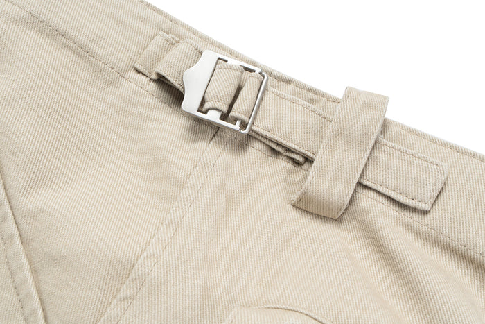 Beige cargo pants waistband close-up with silver buckle strap detail