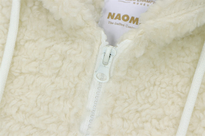 Close-up of the cream sherpa fleece texture, white zipper, and inner garment label