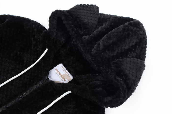 Close-up of the black sherpa fleece hoodie showing the hood, white drawstring, and sewn neck label