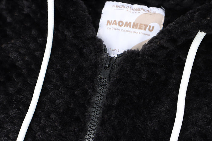 Close-up of the black hoodie front showing the sherpa texture, zipper, white drawstrings, and neck label