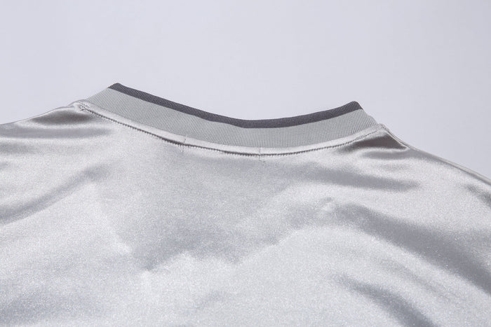 Close-up of light gray ribbed V-neck collar on long sleeve jersey top
