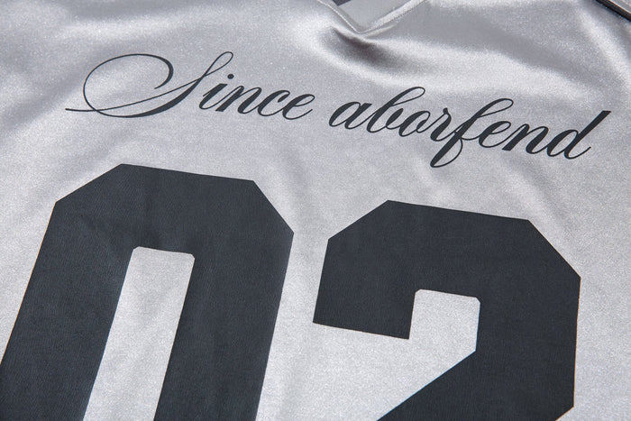 Close-up of front chest graphic reading Since aborfend above 02 on light gray jersey