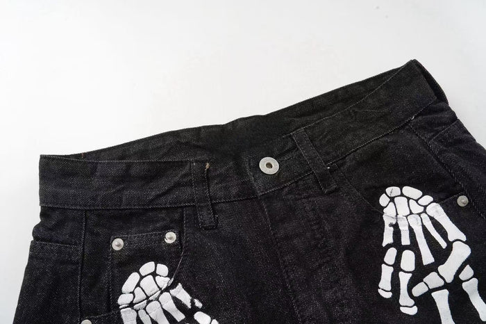 Close-up of black denim waistband with white skeleton hand print and metal rivets