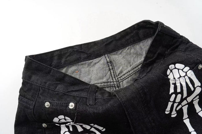 Waistband interior and front pocket area of black denim pants with white skeleton print