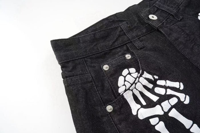Close-up of black denim front pocket and white skeleton hand graphic