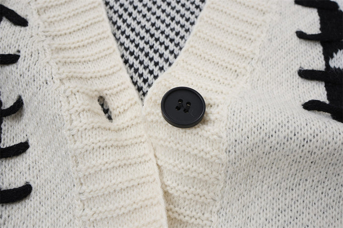 Close-up of cream ribbed cardigan trim with a black button, textured knit, and black-and-white inner pattern