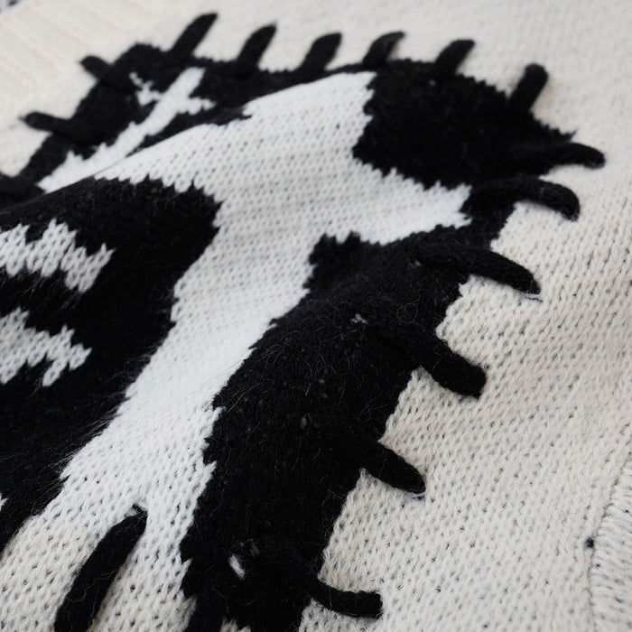 Macro view of raised black-and-white graphic stitching on the cream cardigan knit fabric
