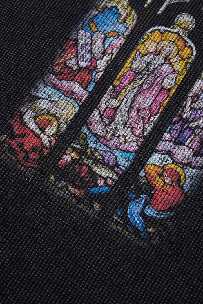Close-up of a black T-shirt with colorful stained glass soul graphic in blue, pink, yellow, and red tones