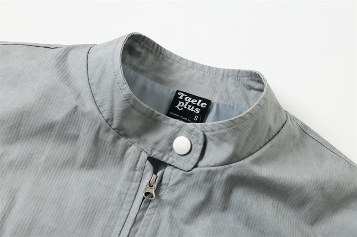 Close-up of the jacket stand collar, snap tab, and front zipper pull