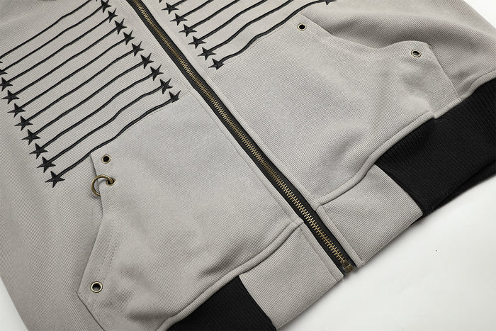 Close-up of the gray hoodie front showing embroidered stripes, star details, zipper, pocket opening, and ribbed hem