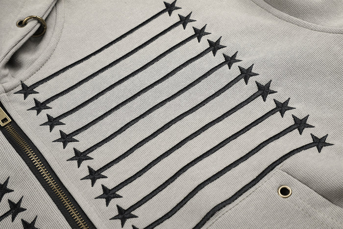 Detailed close-up of black embroidered stars and horizontal stripes on the gray hoodie front