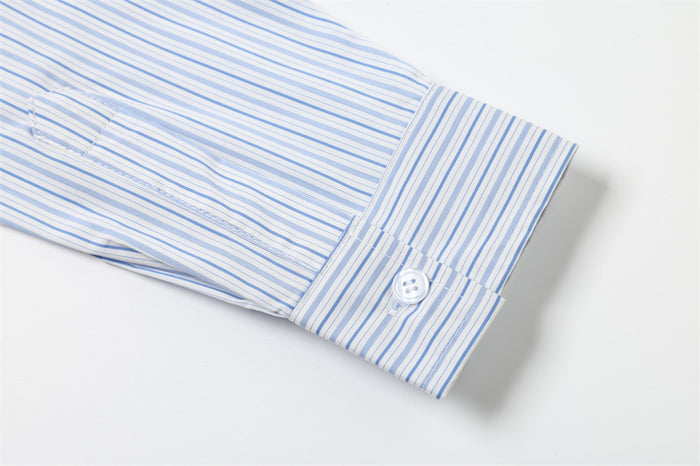 Buttoned shirt cuff on a light blue and white striped sleeve