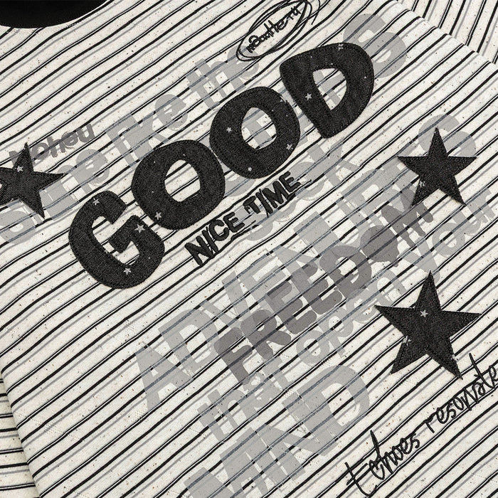 Close-up of the shirt graphic showing textured black GOOD lettering, gray text layers, and star motifs