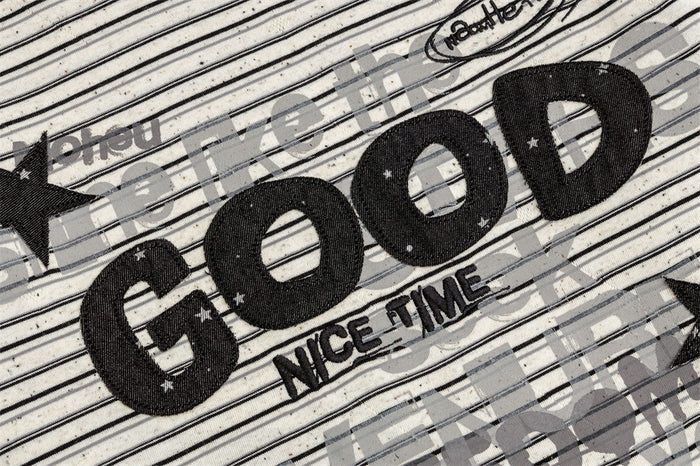 Detailed view of the black GOOD lettering, NICE TIME text, stars, and layered print on striped fabric