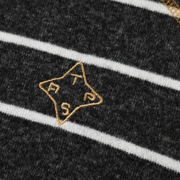 Close-up of a tan embroidered star emblem on the black fleece pullover between white stripes