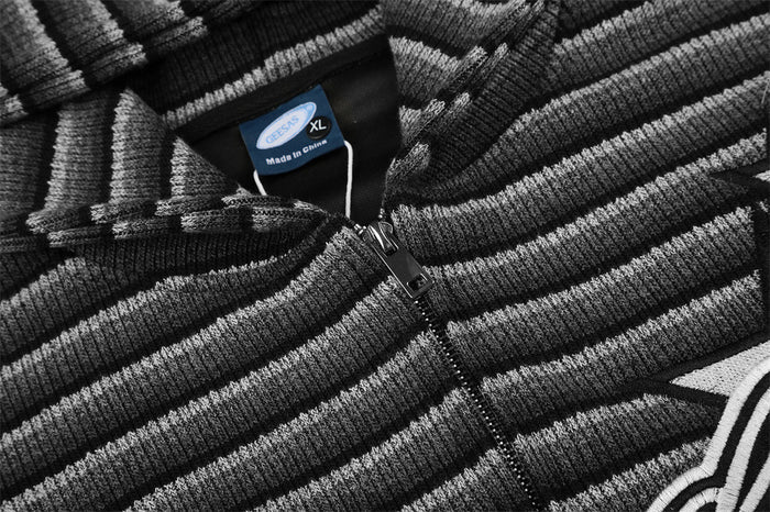 Close-up of the black zipper, striped knit fabric, and sewn-in size label at the hoodie neckline