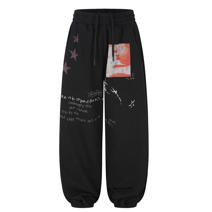Front view of black wide-leg sweatpants with elastic cuffs, star prints, red patch, and white text graphics