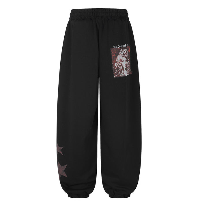 Back view of black wide-leg sweatpants with a small red portrait-style graphic and star prints near the lower leg