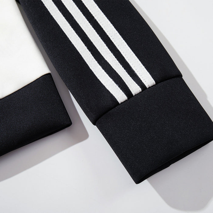 Close-up of a black track jacket sleeve with three white stripes and a ribbed black cuff