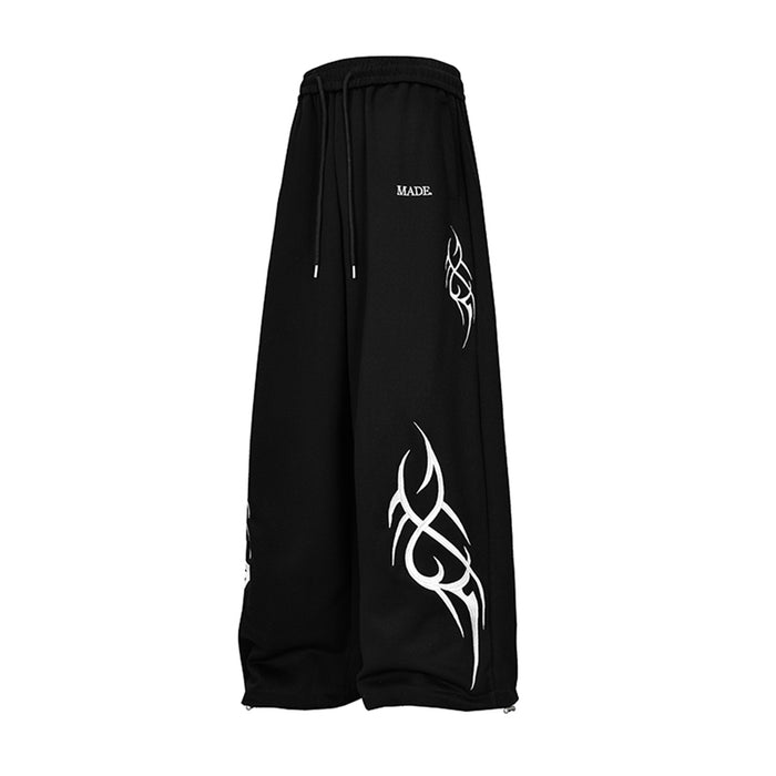 Angled side view of black wide-leg sweatpants with white abstract graphics and a visible drawstring waist