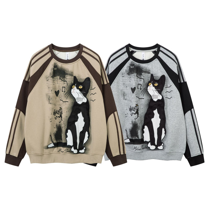 Two tuxedo cat graphic sweatshirts in beige and gray with music notes and contrasting raglan sleeves