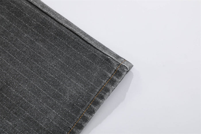 Close-up of dark gray denim hem with stitched edge on wide-leg jeans