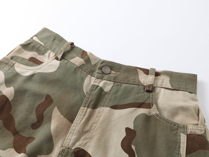 Close-up of camouflage pants waistband with belt loop, pocket edge, and stitched seam