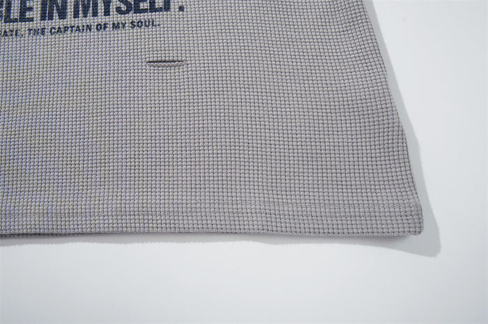 Close-up of light gray waffle knit T-shirt hem with printed front graphic edge