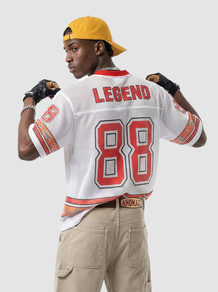 Model wearing a white mesh varsity jersey with red 88 and LEGEND print, paired with a yellow cap and cargo pants