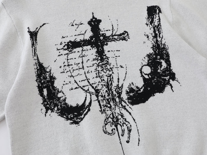 Close-up of black cross graphic on white knit sweater front