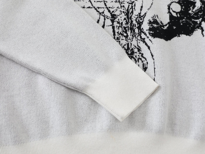 White knit sweater sleeve and front hem with black graphic visible at the edge