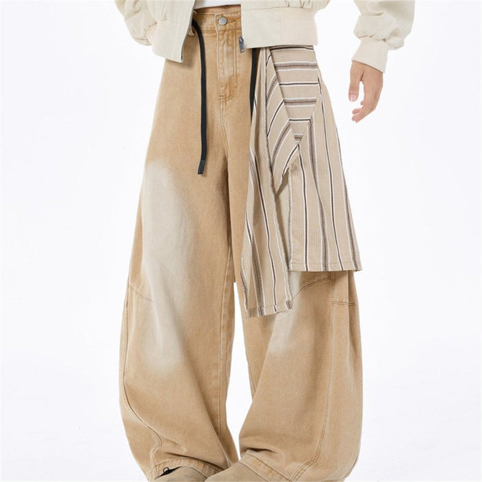 Angled front view of tan wide-leg jeans with striped overlay draped over the right leg