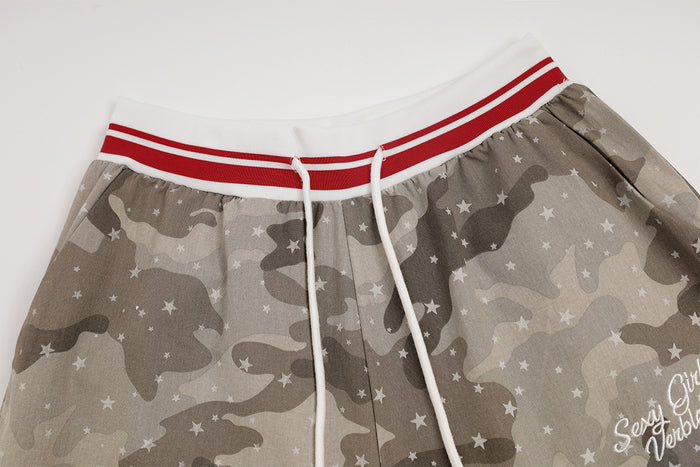 Close-up of gray camouflage pants waistband with red-and-white stripes, white drawstring, and star pattern