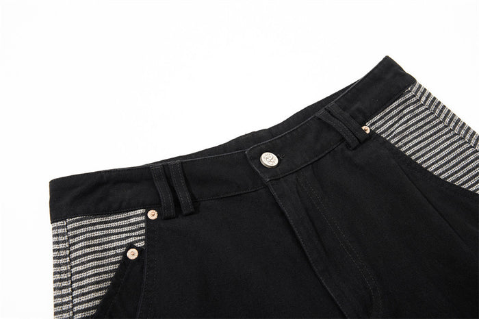 Close-up of the front waistband on black cargo pants with button and striped pocket detail