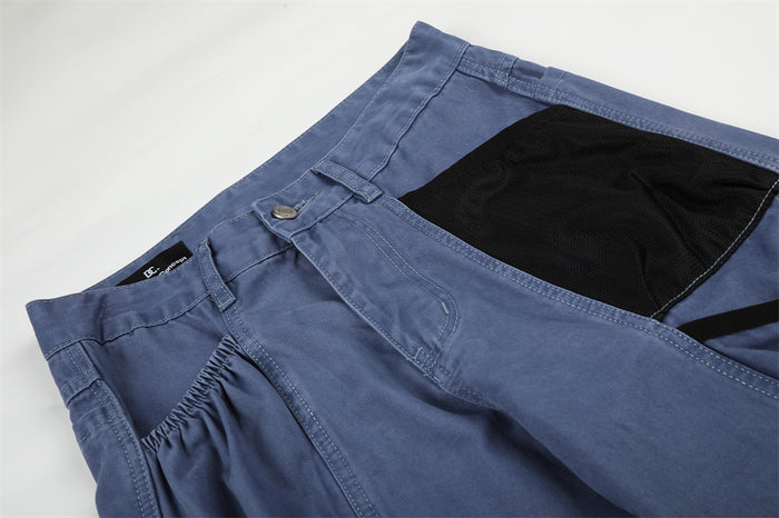 Close-up of blue cargo pants waistband and front pocket details with black contrast panel
