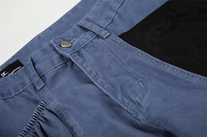 Close-up of blue cargo pants front pocket and waistband button detail
