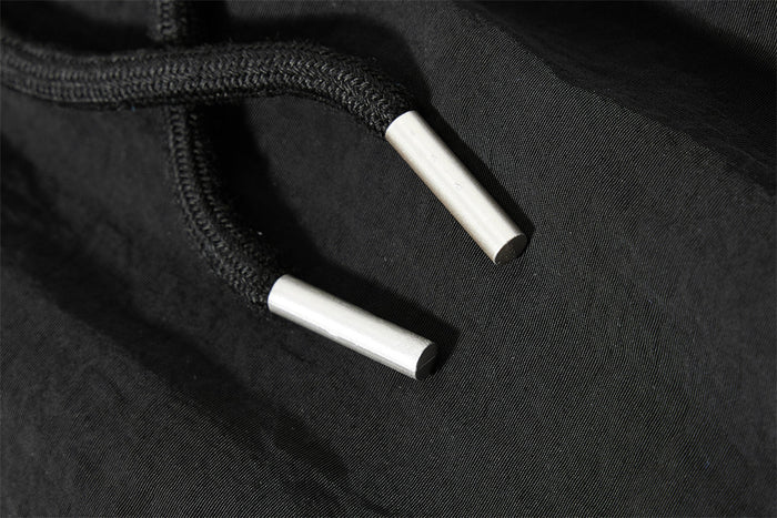 Close-up of black drawstring ends with silver aglets on sweatpants